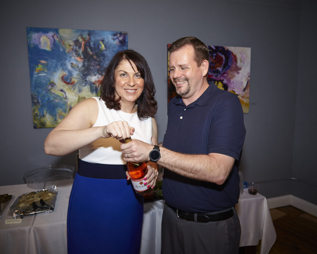 Grand Opening 5/22/2019 - Dolly Towne popping the bottle of wine to celebrate with husband, Rick.